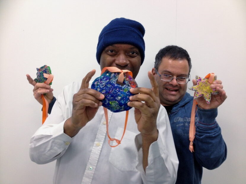 two people showing off their painted clay ornaments