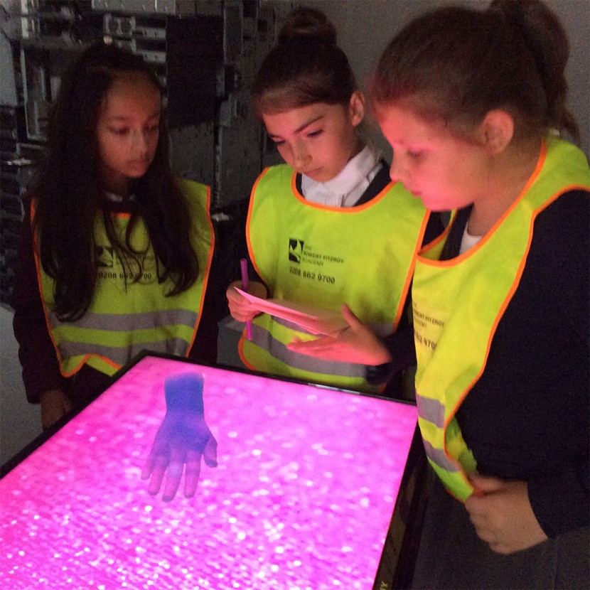 children in high vis vests looking down at the table and hand sculpture