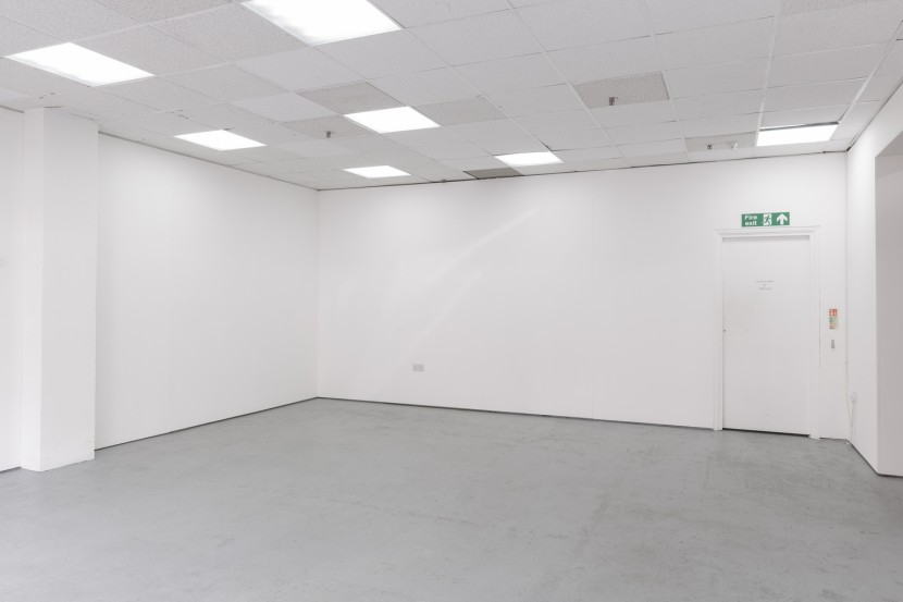 An empty room with white walls and a grey floor