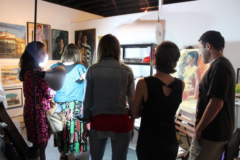 five people look at the piece of art in the spotlight showing a naked body