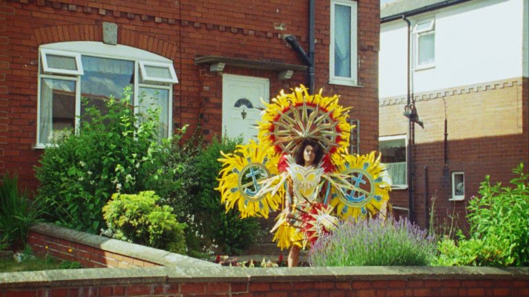 a scarecrow with three large, yellow sunflower esc shapes behind it