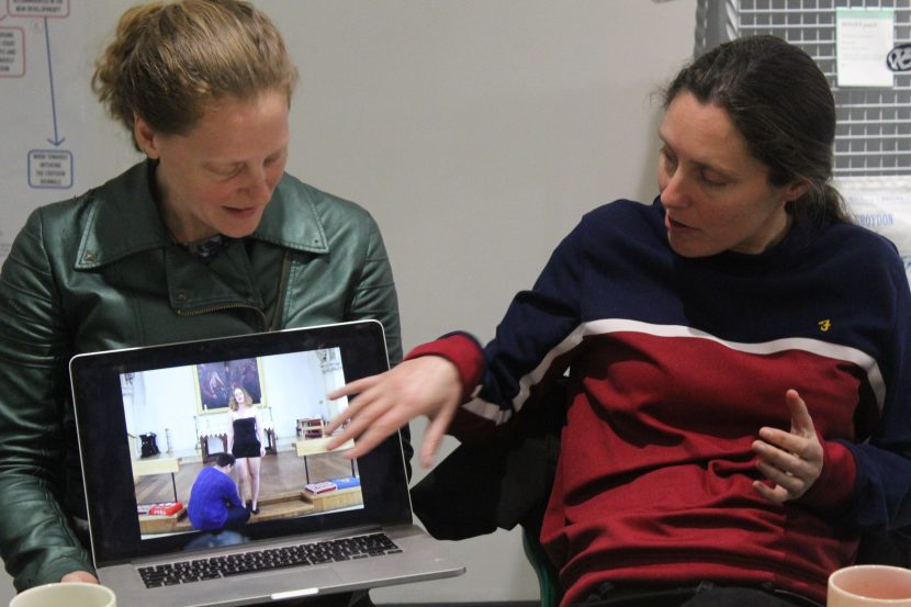 two artists display their work on a laptop, explaining it the laptop shows someone getting assistance with their shoes