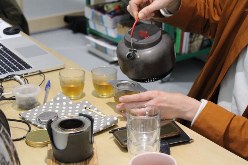 someone pouring more tea through a strainer from a teapot