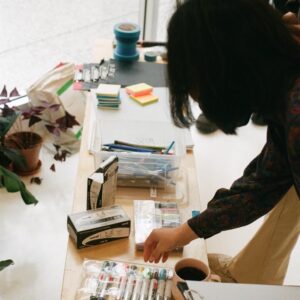 someone choosing from a range of pens laid out on a wooden table