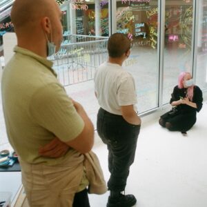 A group of people conversing in front of a window covered in handwritten text