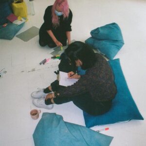 A couple people drawing on the floor with blue pillows