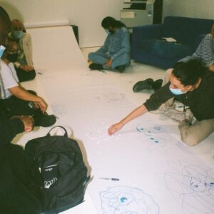 a group of people doodle on a large roll of white paper