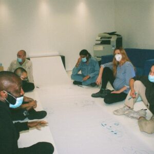 a group of people doodle on a large roll of white paper