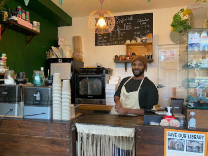 a photo of someone stood behing a cafe counter