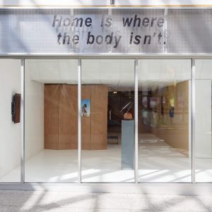 the outside of the TURF building during an exhibition with a sign "home is where the body isnt"