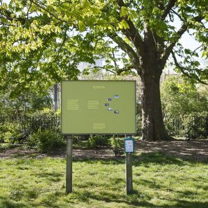 a green sign with a range of information displayed in a park