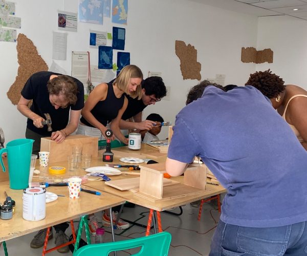 a photograph of the participants working on their bird boxes around a large table