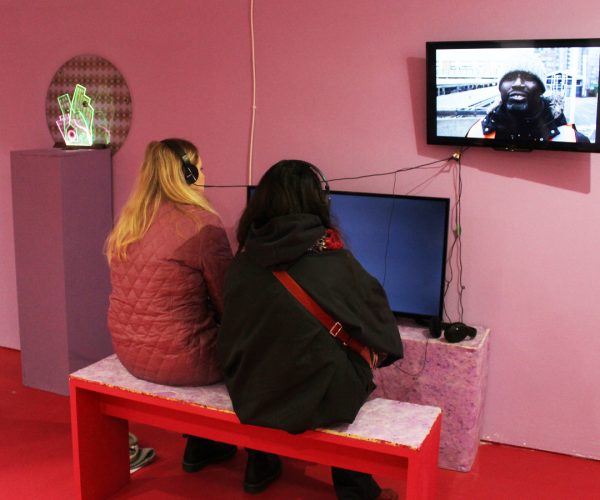 a photograph of exhibition visitors viewing films on two monitors