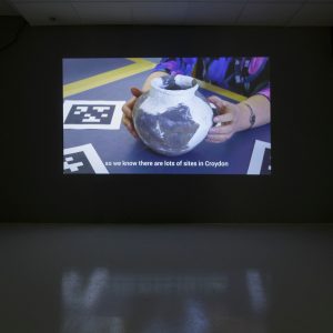 projection of a ceramic pot. subtitles read "so we know there are lots of sites in croydon"